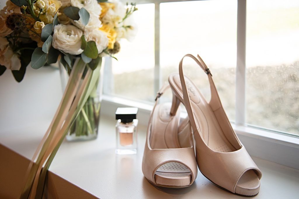 Shoes and perfume bottle with wedding bouquet on a window sill